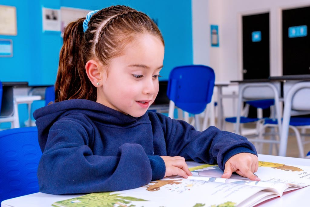 Niña leyendo en un centro Kumon, con postura adecuada, desarrollando habilidades de comprensión y síntesis. - Peru