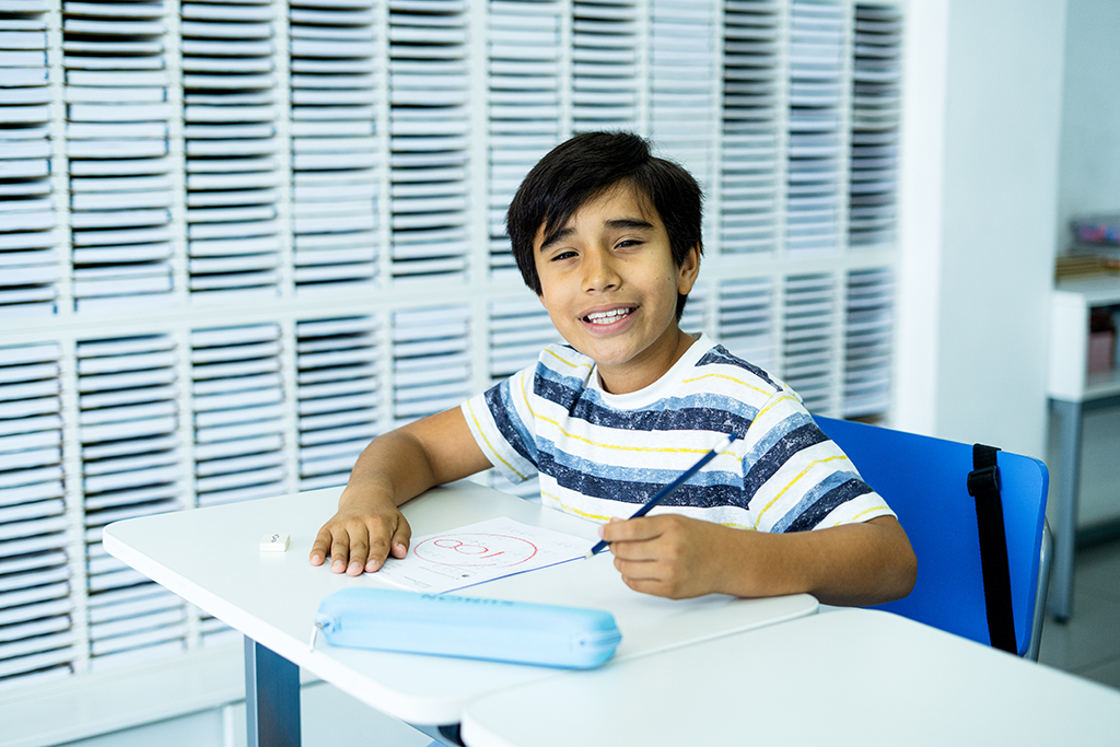 Alumno sentado, sosteniendo un lápiz y sonriendo en el aula de un centro Kumon-Uruguay