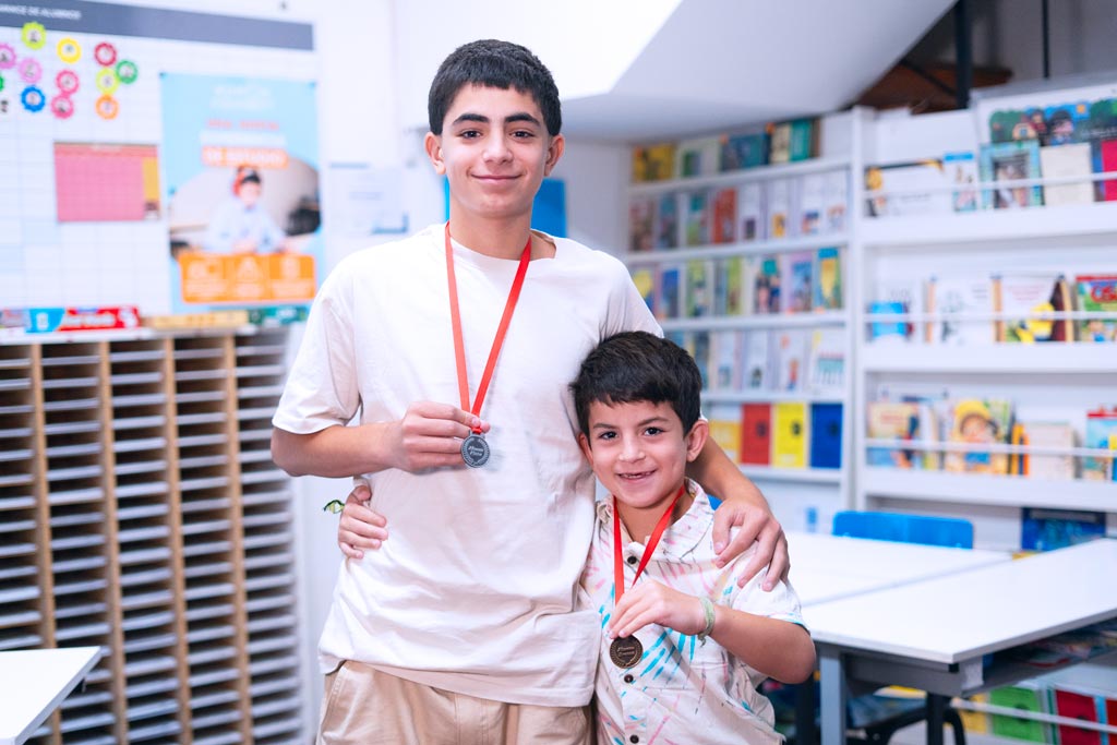 Dos estudiantes en un centro Kumon mostrando orgullosamente sus medallas por logros educativos-Uruguay